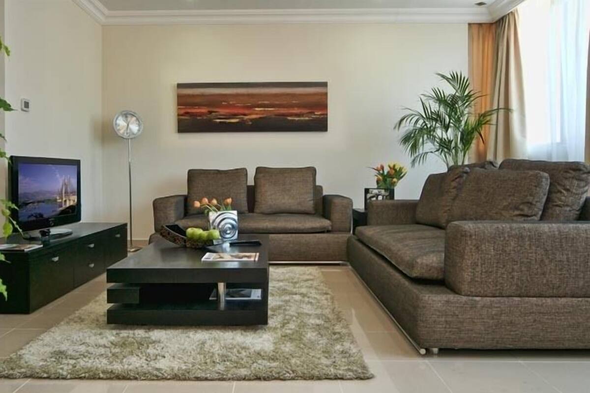 A modern living room with a flat-screen TV, two sofas, a coffee table, and a painting on the wall.