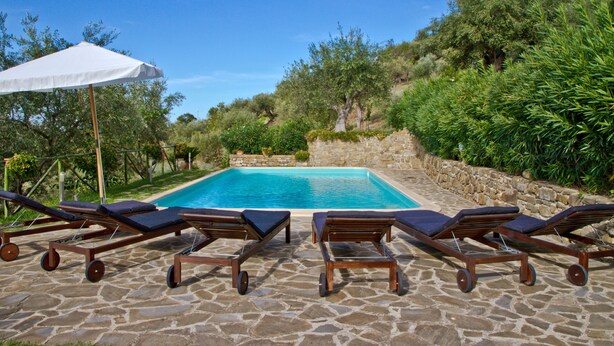 Une piscine avec des chaises longues et un parasol blanc.