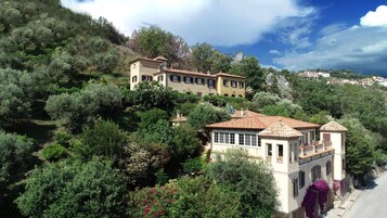 Villa en una ladera con varias construcciones, rodeada de exuberante vegetación y árboles.
