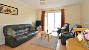 A living room with a sofa, a coffee table, and a TV. - Lynfield Guest House (Galway)