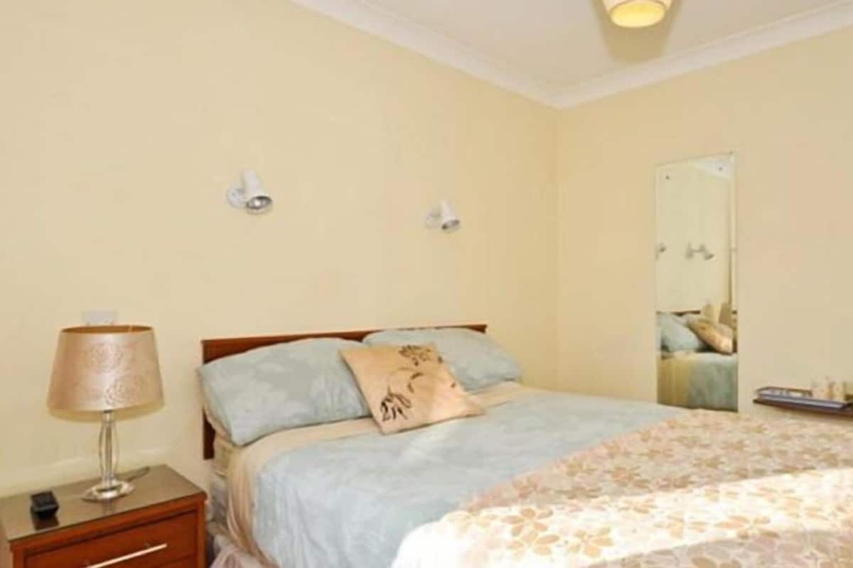 A bedroom with a bed, bedside lamp, and a mirror.