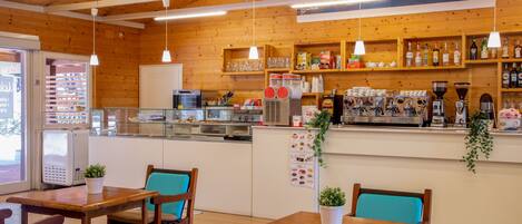 A cozy cafe with wooden interior, tables, chairs, and a coffee bar.