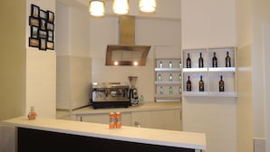 A modern kitchen with a coffee machine, a shelf with bottles, and a counter with two cans. - Palma Residences In Rome (Rome)