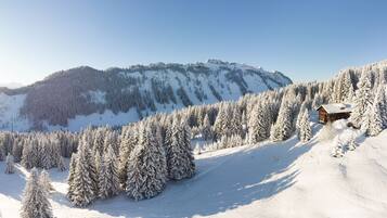 A snow-covered mountain landscape with a wooden cabin.