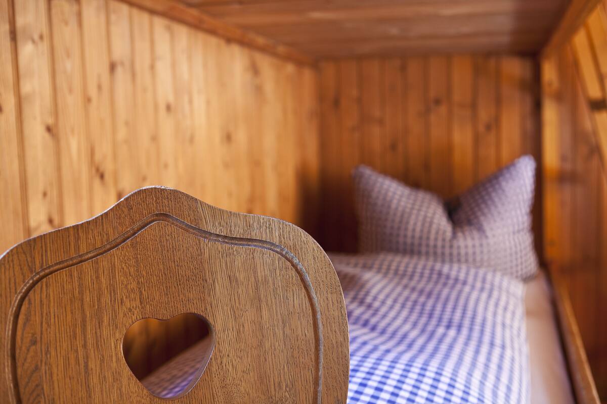 A wooden cabin interior with a bed and a guitar.