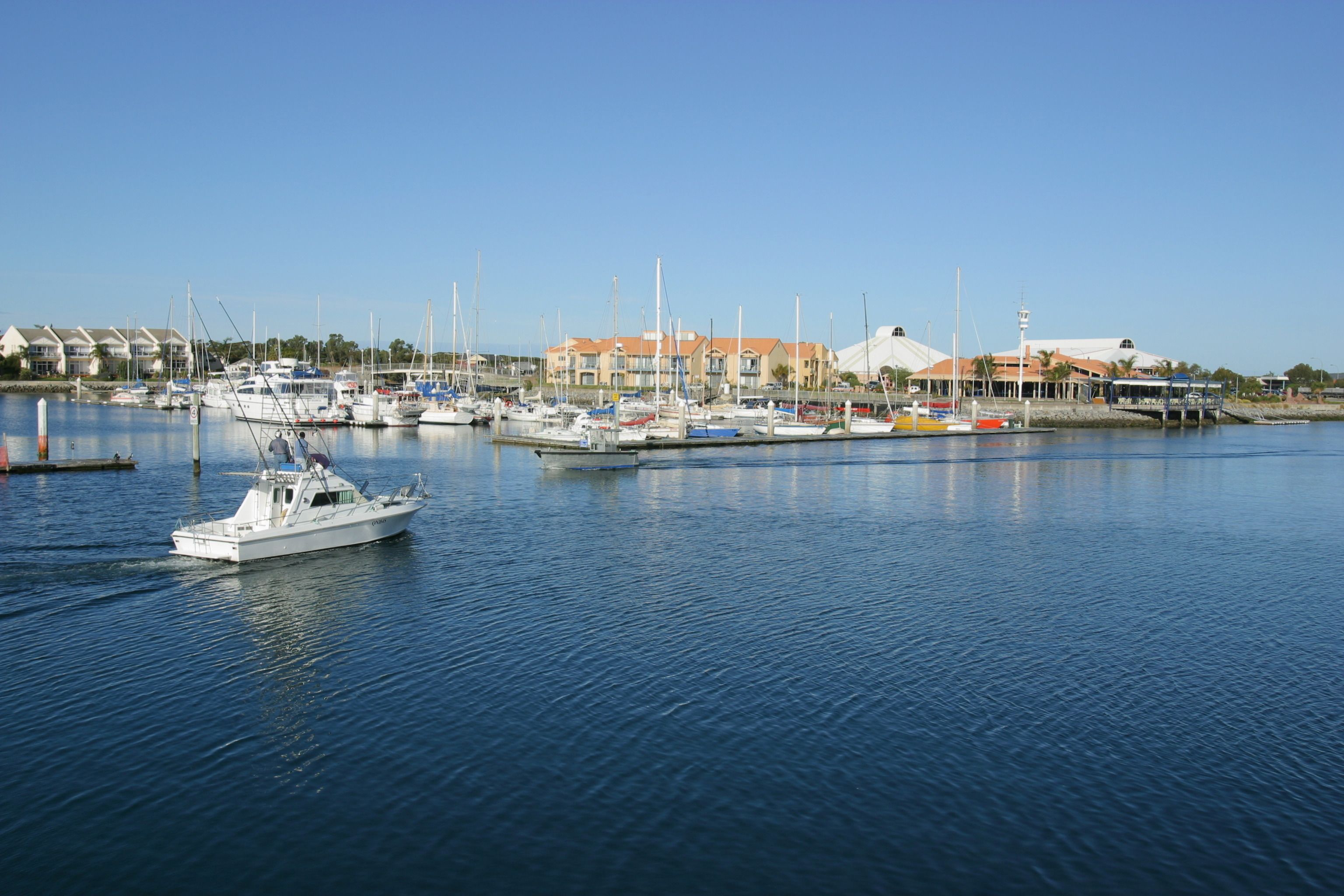 A marina with boats docked and a building with a white roof in the background.