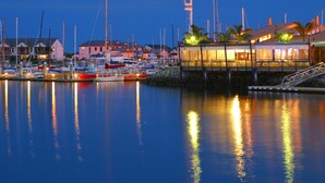 A marina with boats docked, a building with a covered area, and a clear sky. - The Marina Hotel (Port Lincoln)