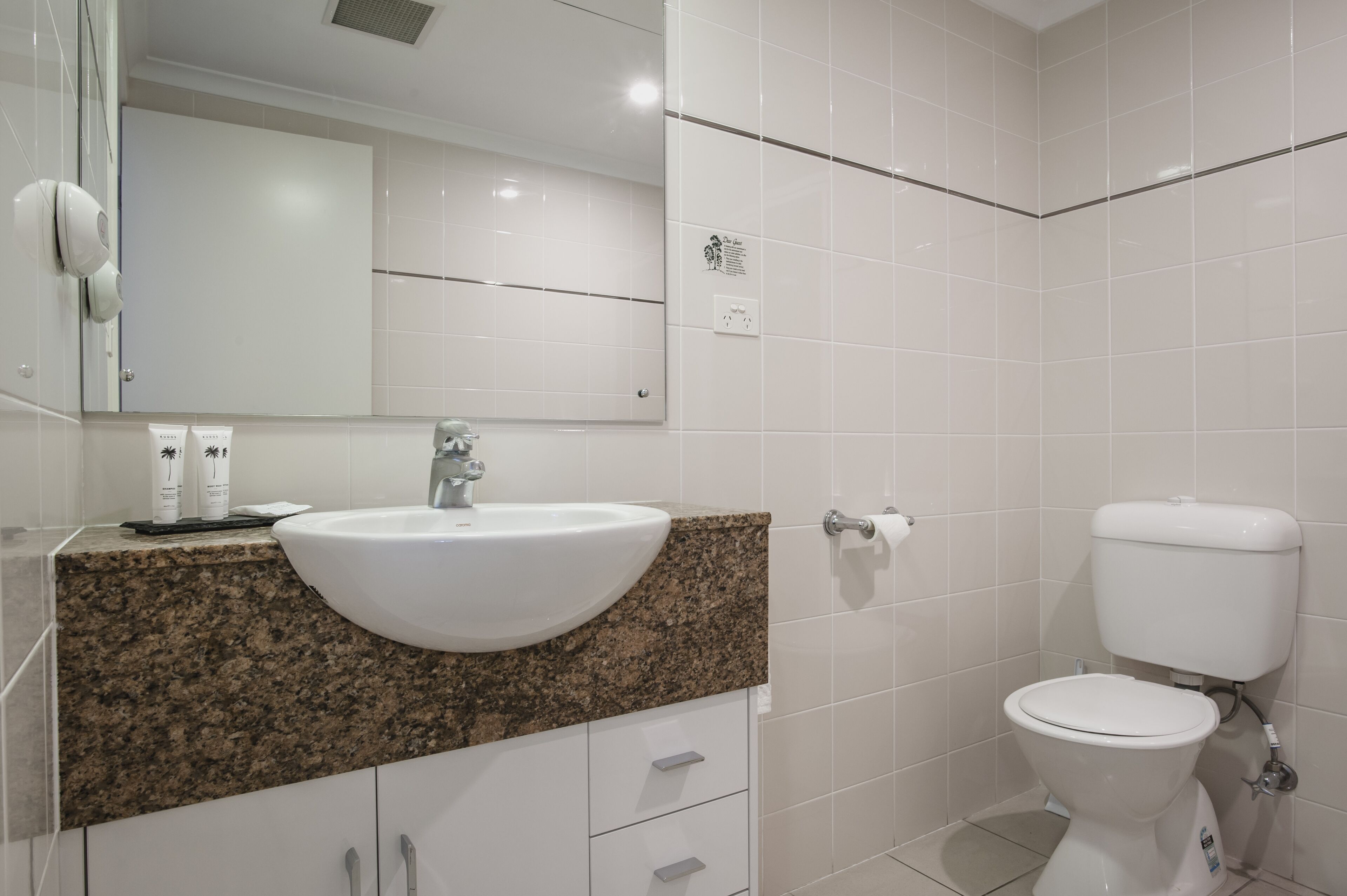 A bathroom with a granite countertop, white sink, and a toilet.
