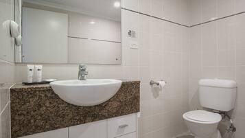 A bathroom with a granite countertop, white sink, and a toilet.
