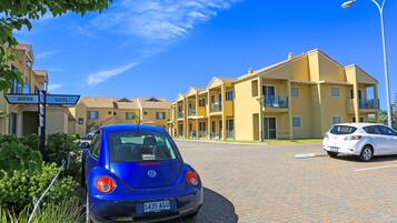 Un'auto blu Volkswagen parcheggiata di fronte a un edificio giallo con cartelli che indicano 'Marina' e 'Suites'.