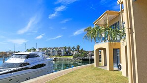 A marina with a yacht docked, a building with a balcony overlooking the water, and a clear blue sky. - The Marina Hotel (Port Lincoln)
