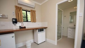 A compact hotel room with a kitchenette, a small refrigerator, a microwave, a trash bin, and a shower area. - All Seasons Country Lodge (Taree South)