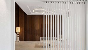 A modern interior with a white partition, a hanging light fixture, and a wicker floor lamp. - Ramada by Wyndham Hamilton City Center (Hamilton)