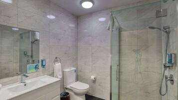 Une salle de bain moderne avec une douche à parois de verre, un lavabo blanc et des toilettes.