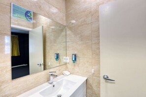 A bathroom with a large mirror, sink, and door, featuring a tiled wall.