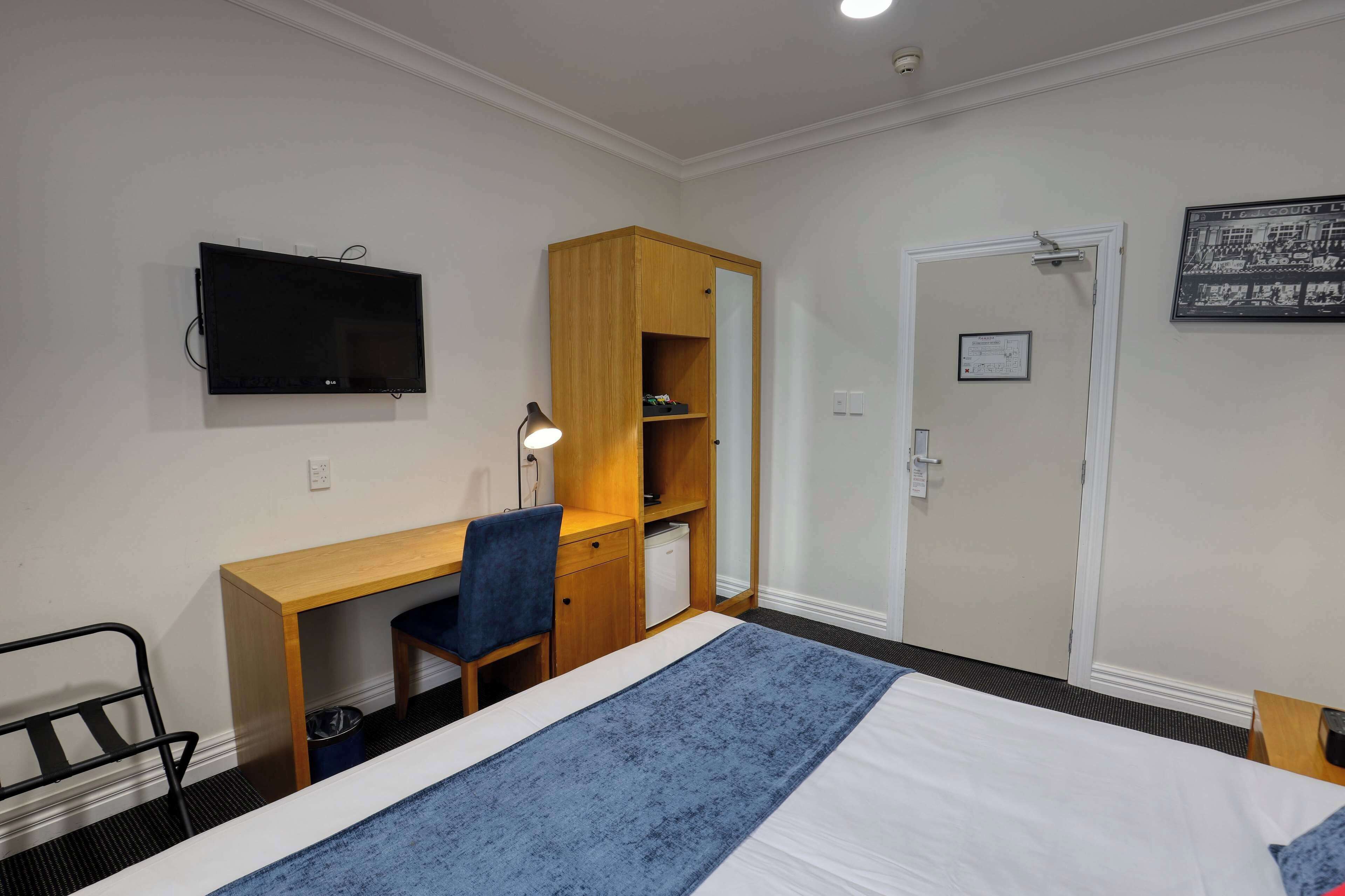 Une chambre d’hôtel comprenant un lit, un bureau, une chaise, une télévision, une armoire et une porte.