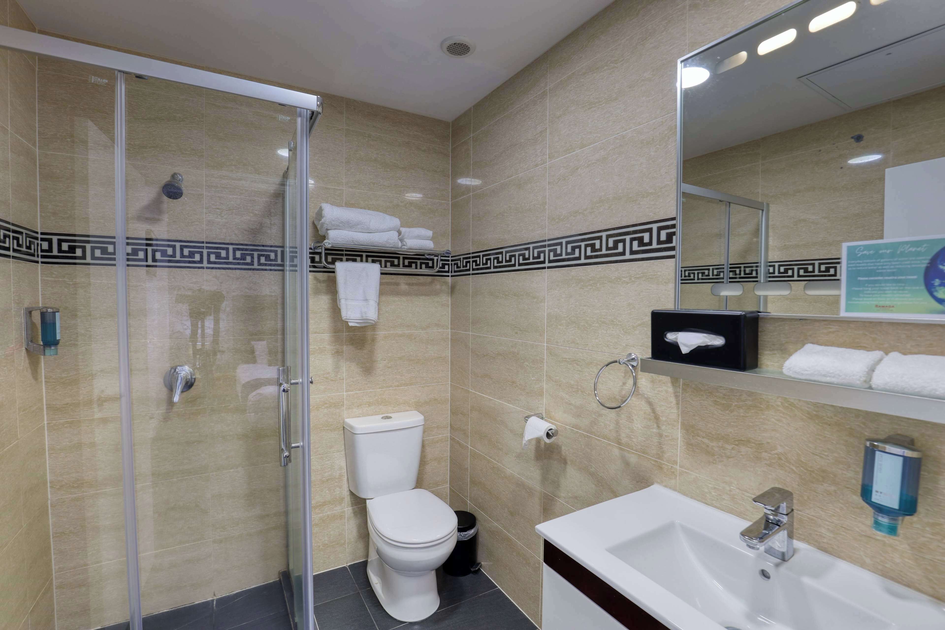 Een moderne badkamer met een douchecabine van glas, een wit toilet, een wastafel met spiegel en een handdoekrek.