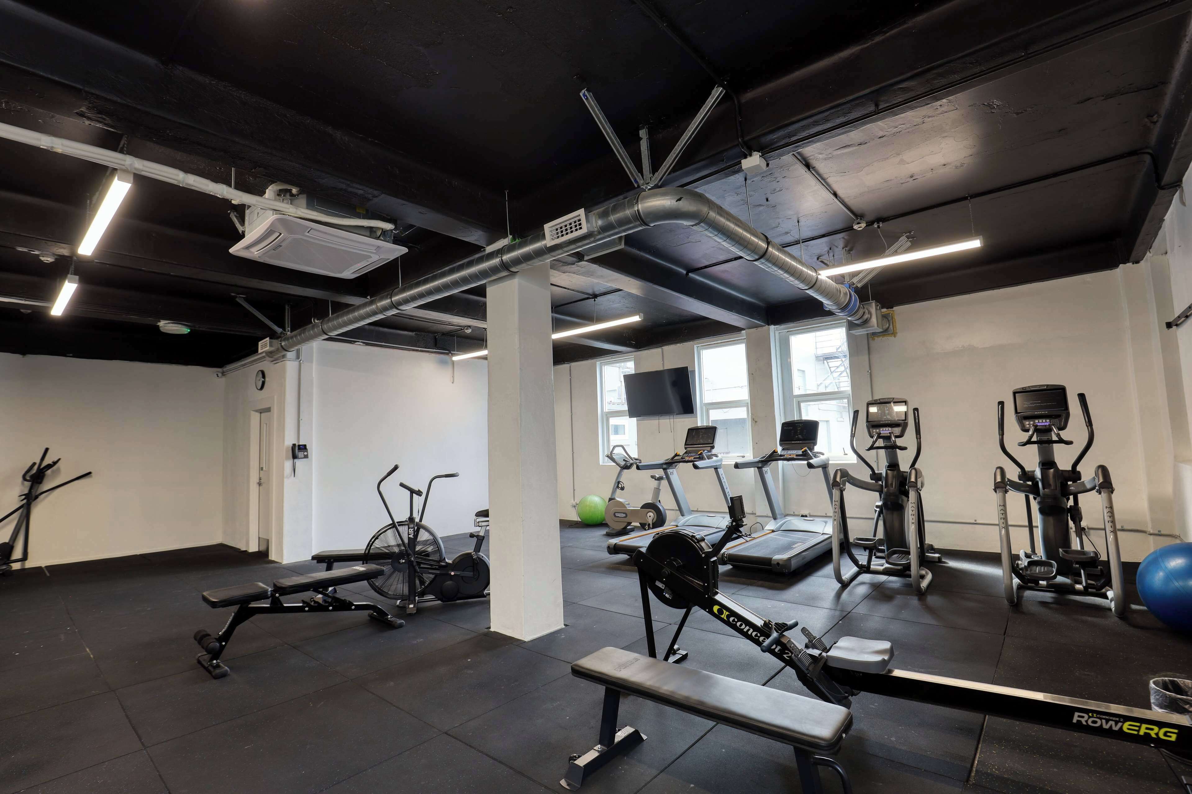 Un gimnasio con equipo de ejercicio, una banca y una cinta de correr.