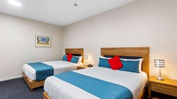 A hotel room with two beds, each with a wooden headboard, a nightstand, and a lamp.