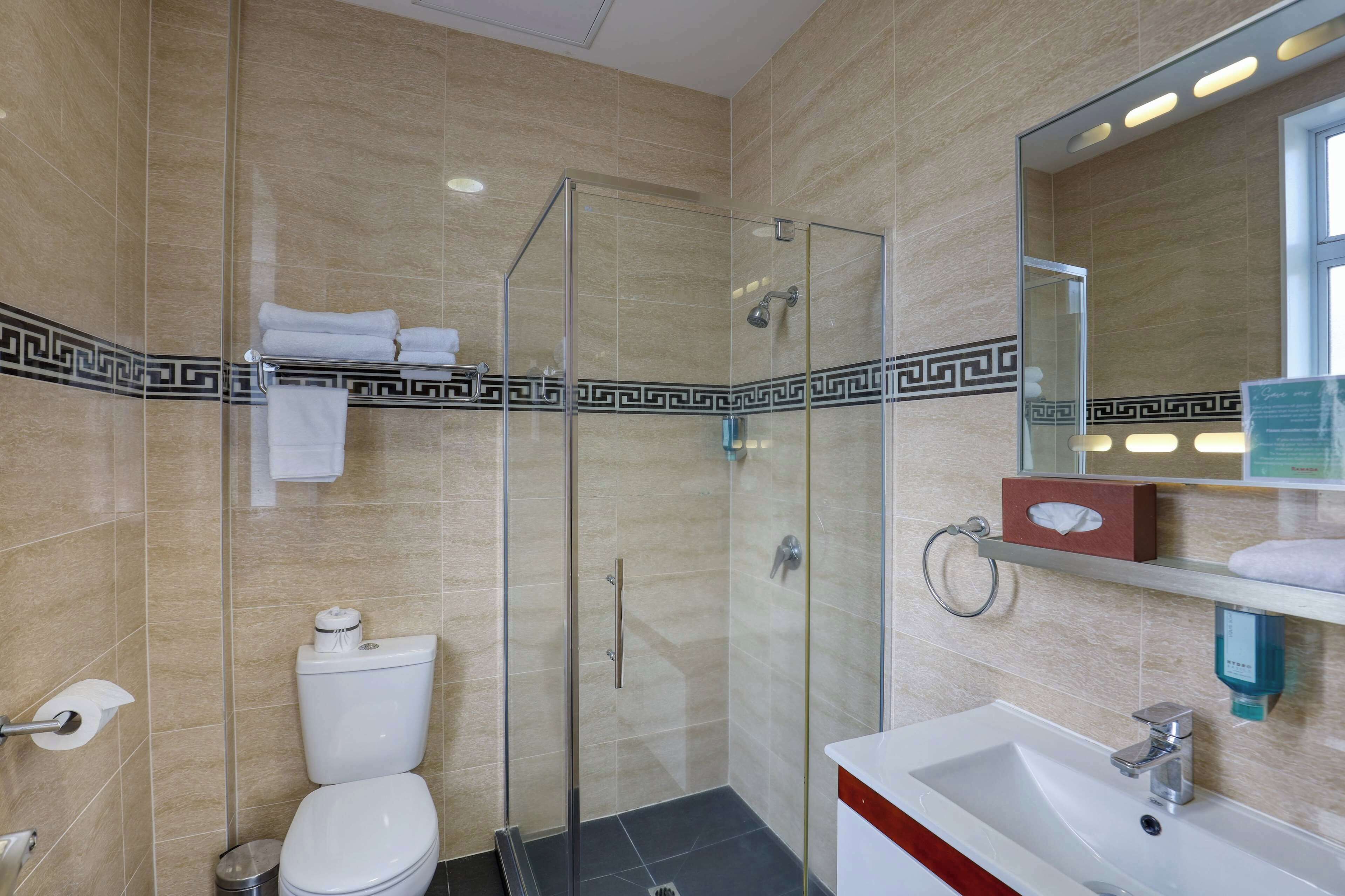 A modern bathroom with a glass-enclosed shower, a white sink, and a toilet.