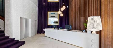 A reception area with a white reception desk, purple curtains, and a wooden panel wall.