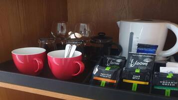 A coffee station with red cups, a coffee pot, and various coffee pods.