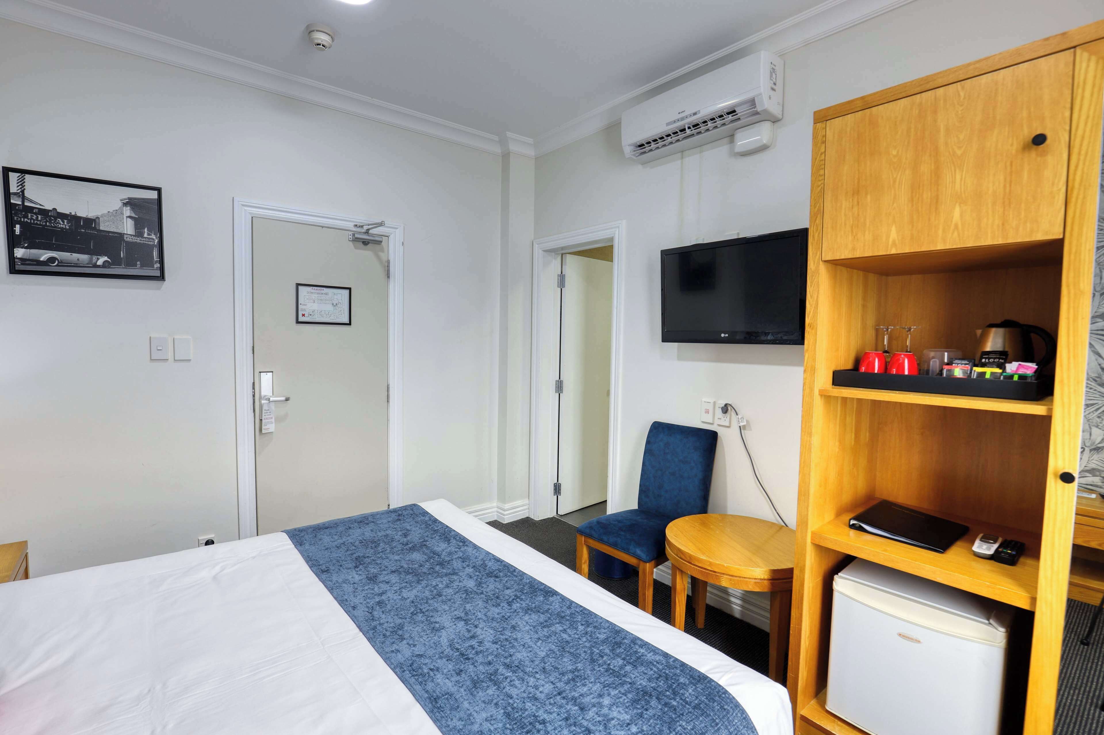A hotel room with a bed, a desk, a chair, a television, and a mini-fridge.