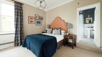 A bedroom with a large bed, a nightstand, a dresser, and a window with curtains.