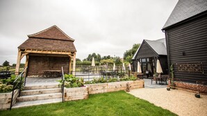 Un patio con mobiliario exterior, una pérgola de madera y un edificio de ladrillo.