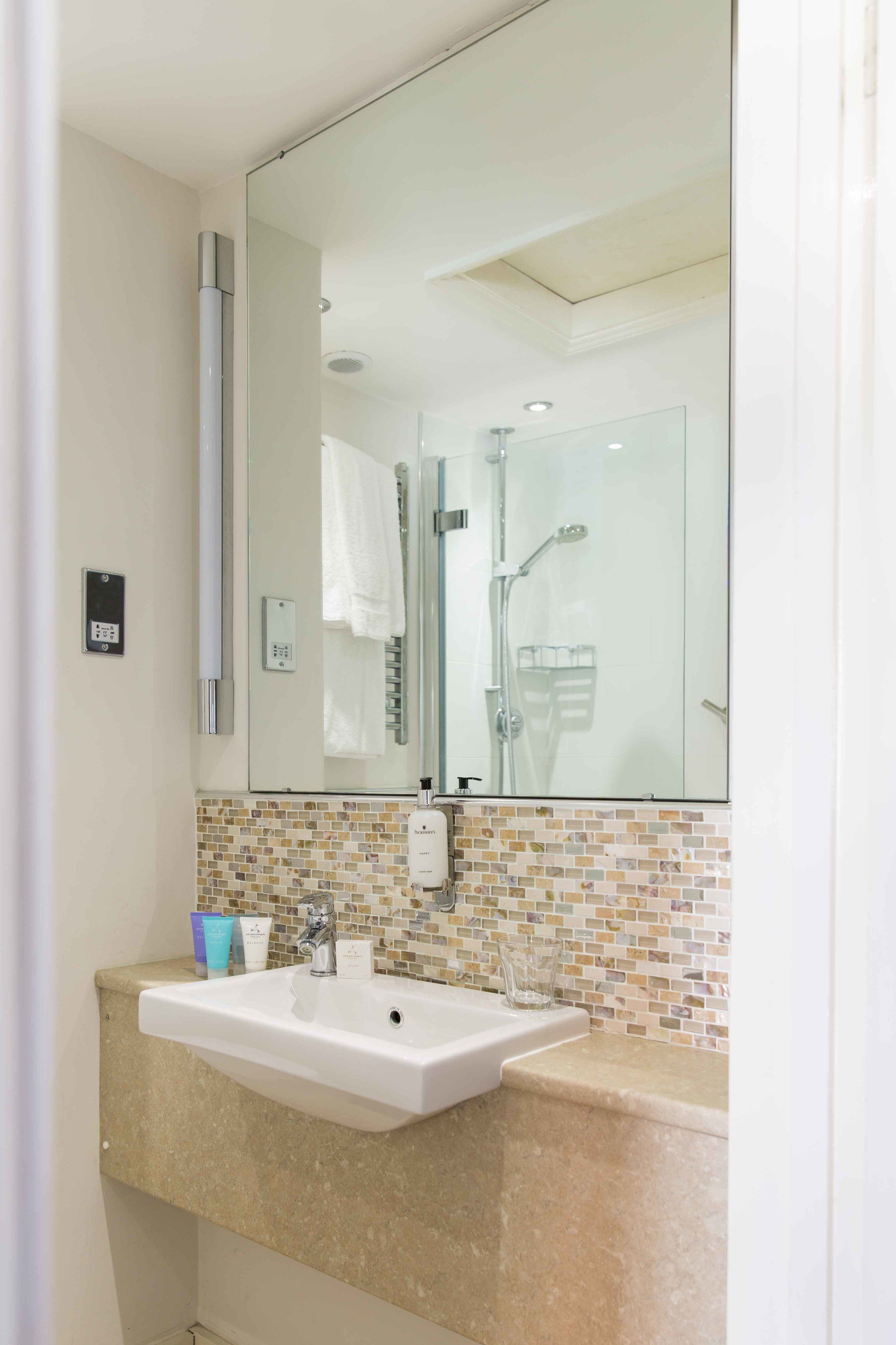 A bathroom with a white sink, a mirror, and a shower.