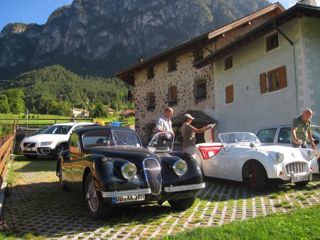 Une voiture ancienne est garée devant un immeuble, avec une chaîne de montagnes en arrière-plan.