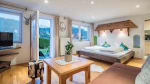 Ein Schlafzimmer mit einem Bett, einem Holztisch, einem Fernseher und Bergblick.
