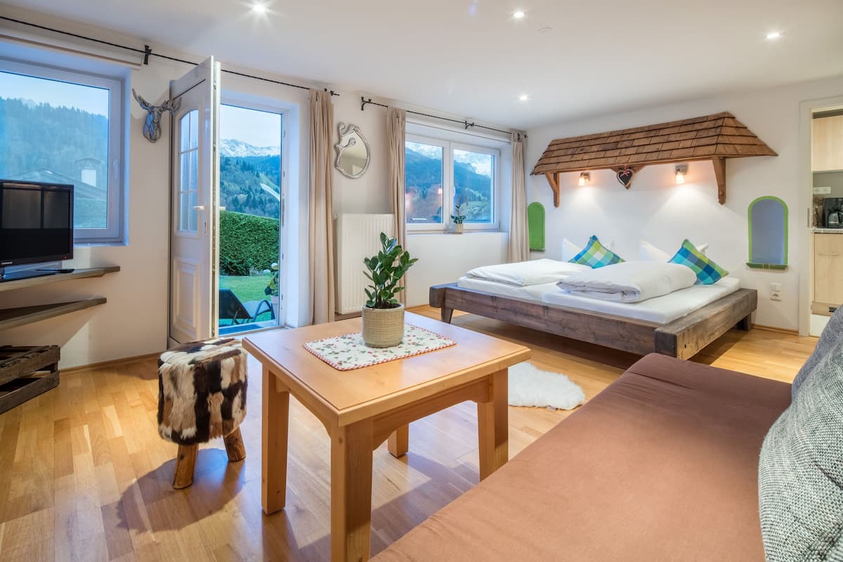 Ein Schlafzimmer mit einem Bett, einem Holztisch, einem Fernseher und Bergblick.