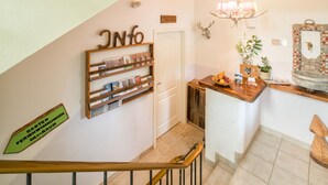 Eine Treppe mit hölzernem Geländer, ein an der Wand befestigtes Regal mit Büchern und gerahmten Fotos, eine Chandelüster und ein Schild, das einen Ski-Raum kennzeichnet.