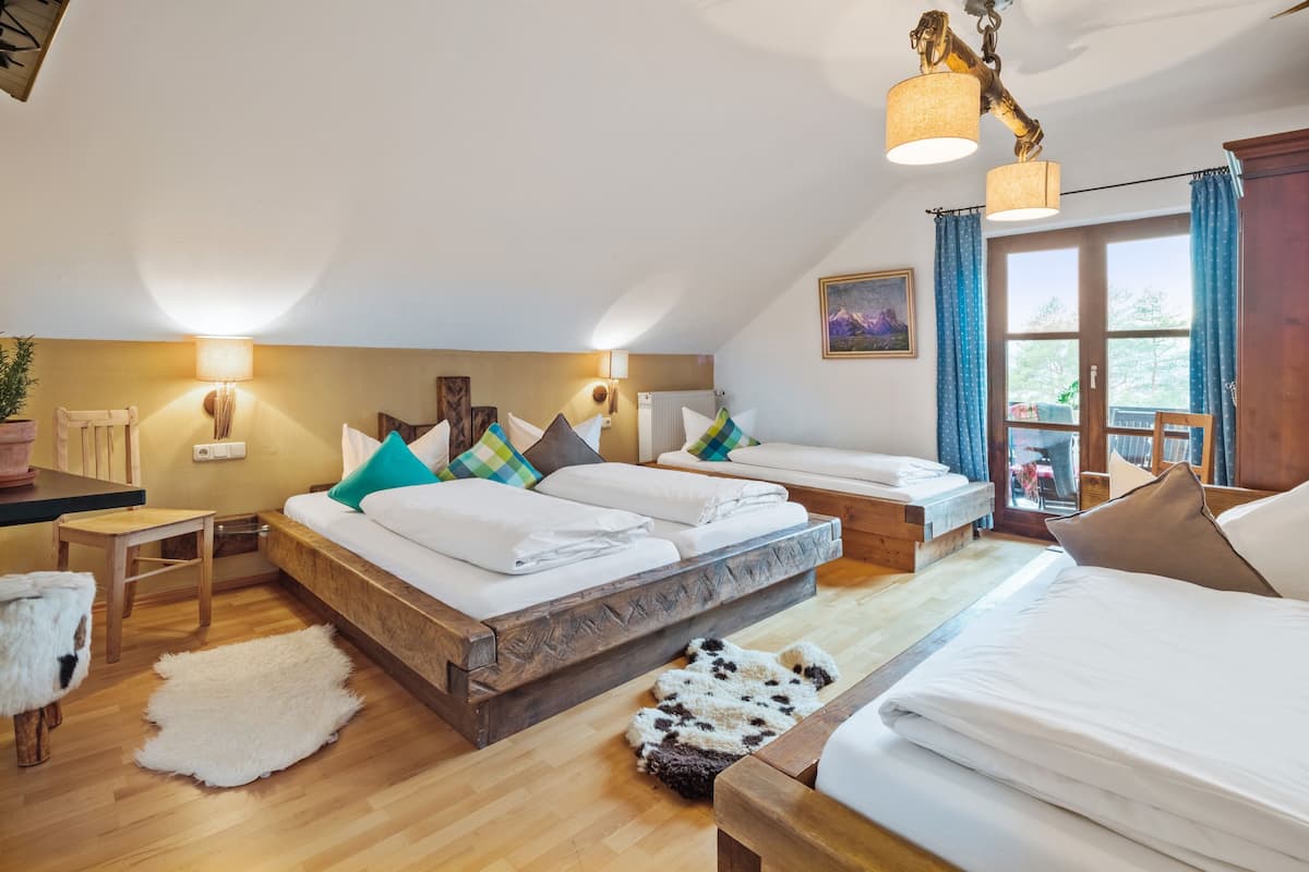 Ein geräumiges Schlafzimmer mit einem großen Bett, einem kleineren Bett und einem Schlafsofa. Zwei Wandlampen und eine Deckenleuchte sind vorhanden.