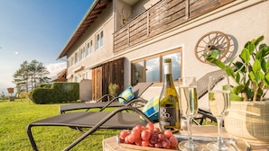 Ein Haus mit Balkon, eine Weinflasche, Gläser und eine Schüssel mit Trauben auf der Rasenfläche.