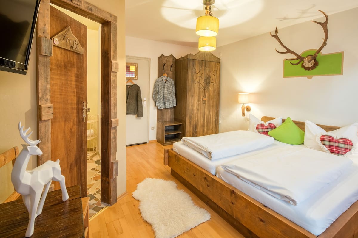 Ein Zimmer mit einem hölzernen Bett, einer weißen Hirschskulptur, einem aufgehängten Hirschkopf und einem Fernseher an der Wand.