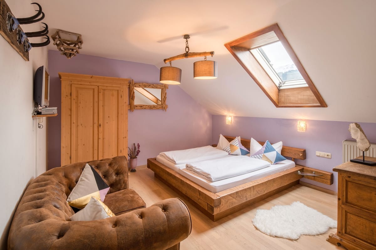 Ein Schlafzimmer mit einem Schlafpodest, Holzmöbeln, einem weißen Teppich und einem Dachfenster.