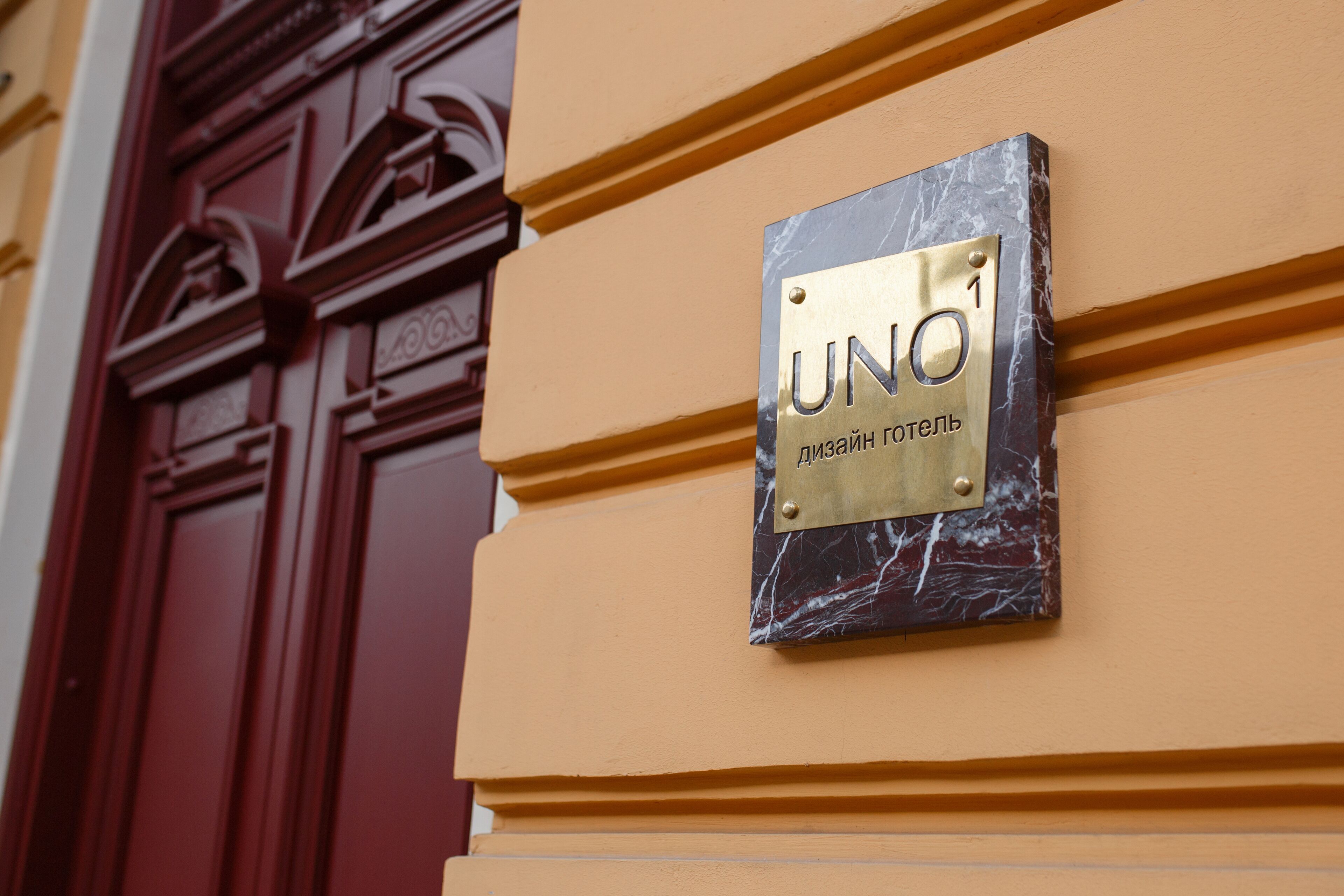 A plaque with "UNO" and "Дизайн гостини" on a building facade.