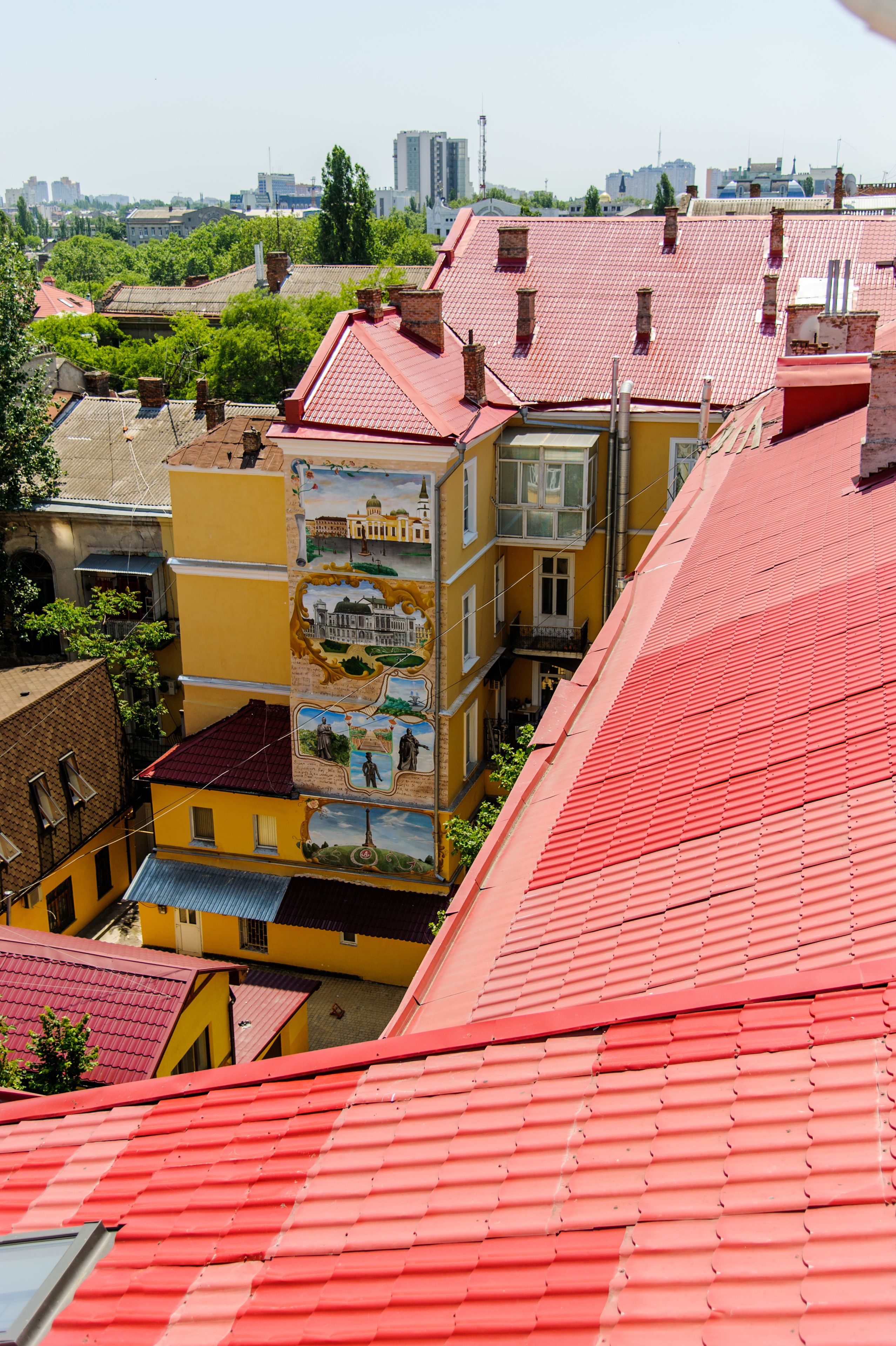 A multi-story building with a red roof and a mural on one side.