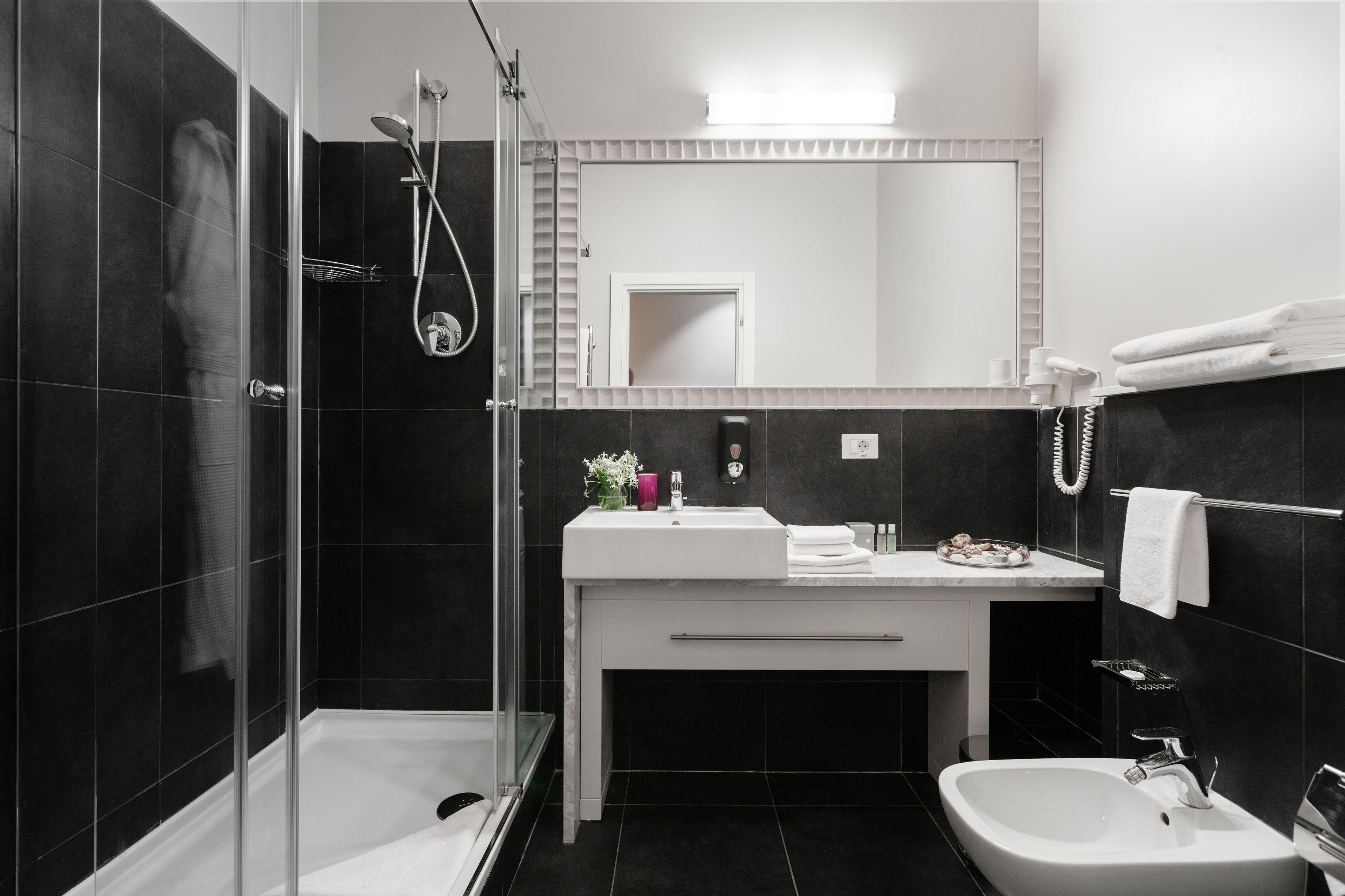 A modern bathroom with a glass shower enclosure, a white sink, and a bidet.