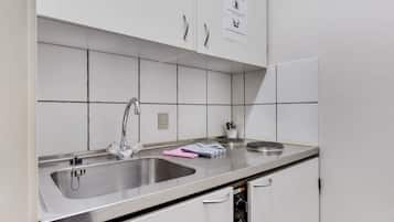 Una cocina con dos lavamanos de acero inoxidable, un grifo y un cartel en la pared.