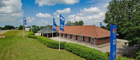 A hotel with a red roof, multiple flags, and a well-maintained lawn.