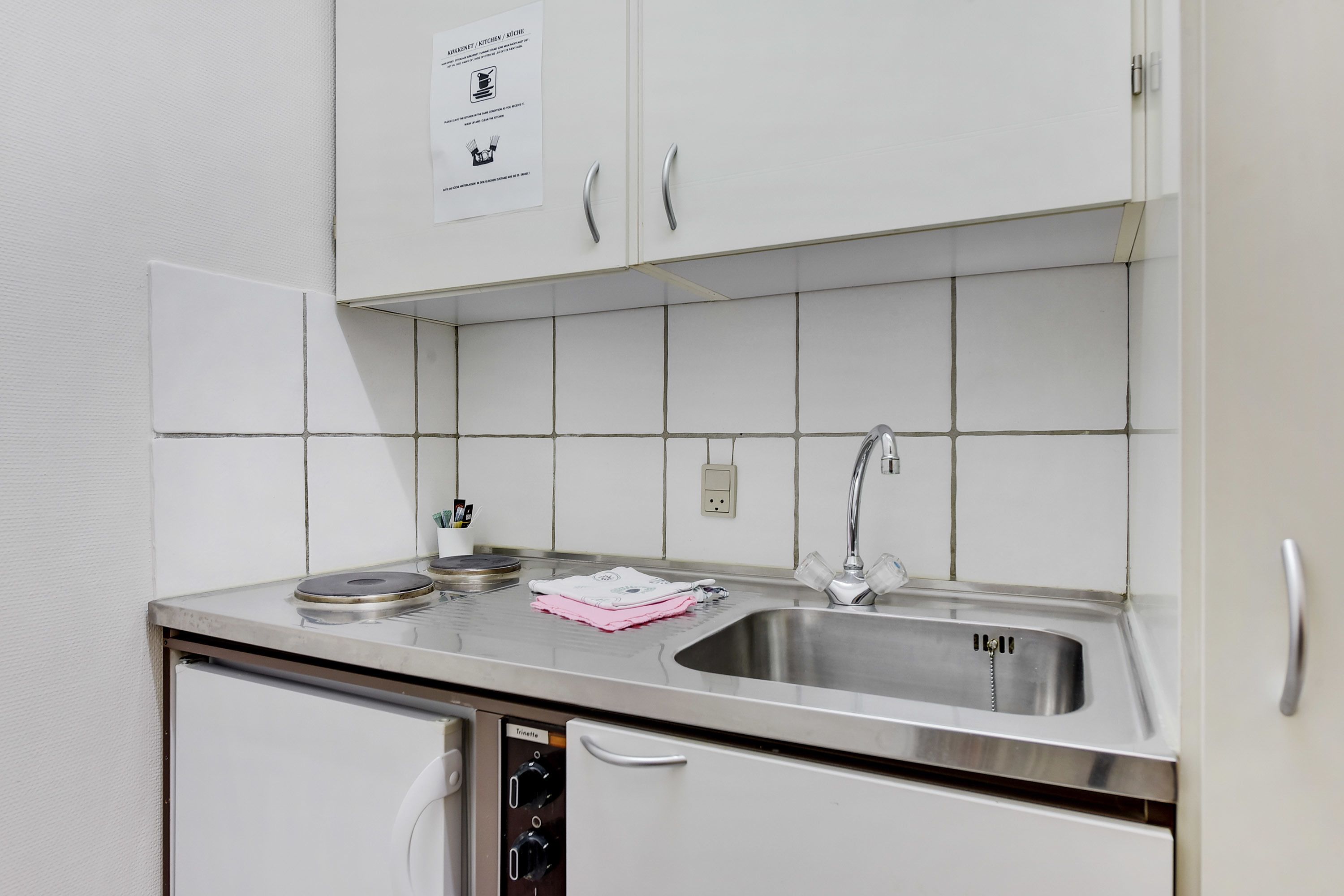 A modern kitchen with white cabinets, a stainless steel sink, and a dishwasher.