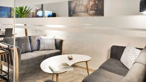 A modern living room with a grey sofa, a white coffee table, and a glass partition.