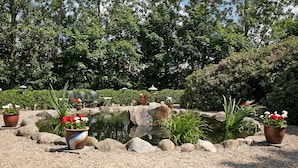 A garden with a pond, surrounded by rocks and potted plants.