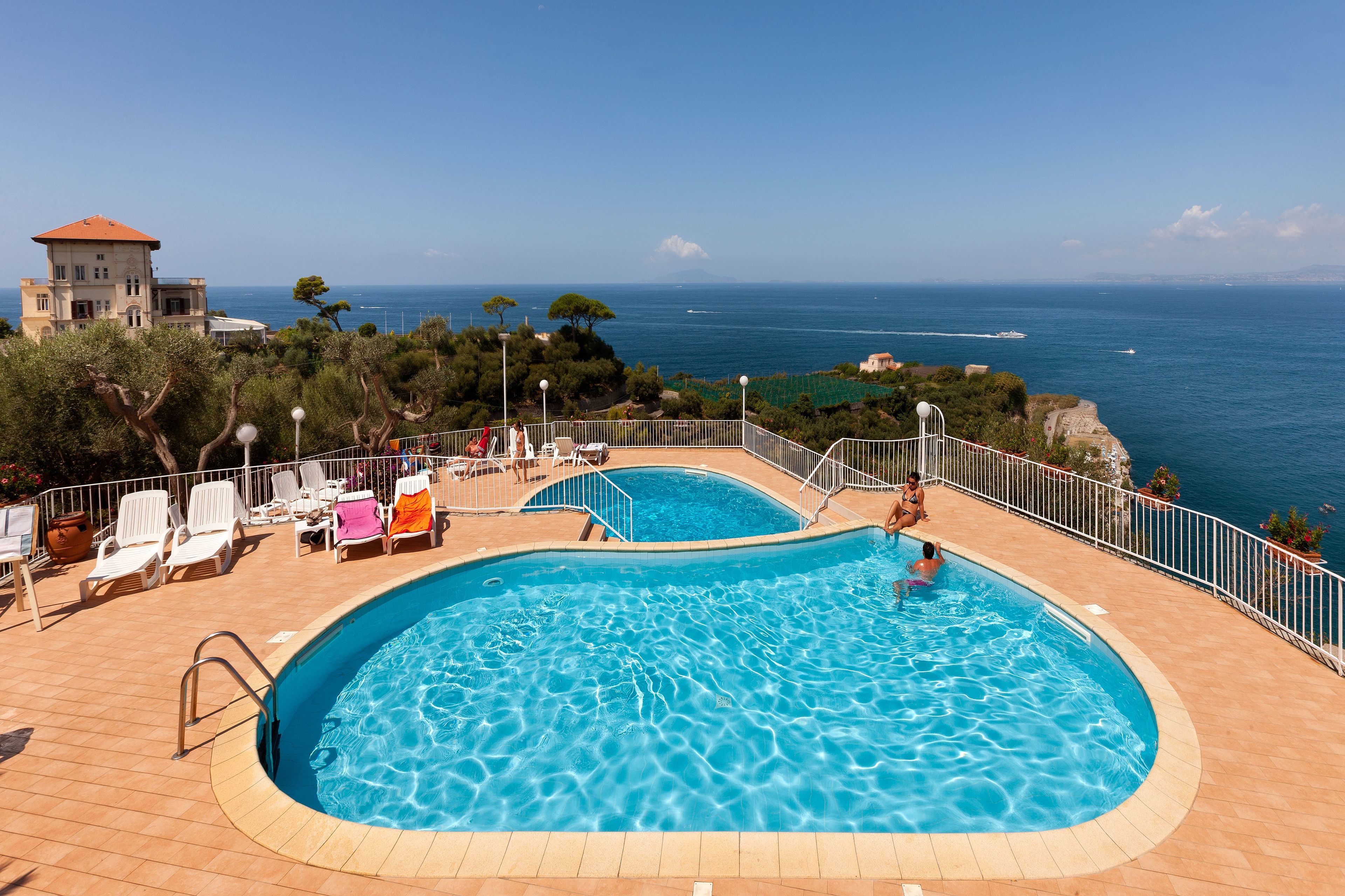 Een seizoensgebonden buitenzwembad, ligstoelen bij het zwembad