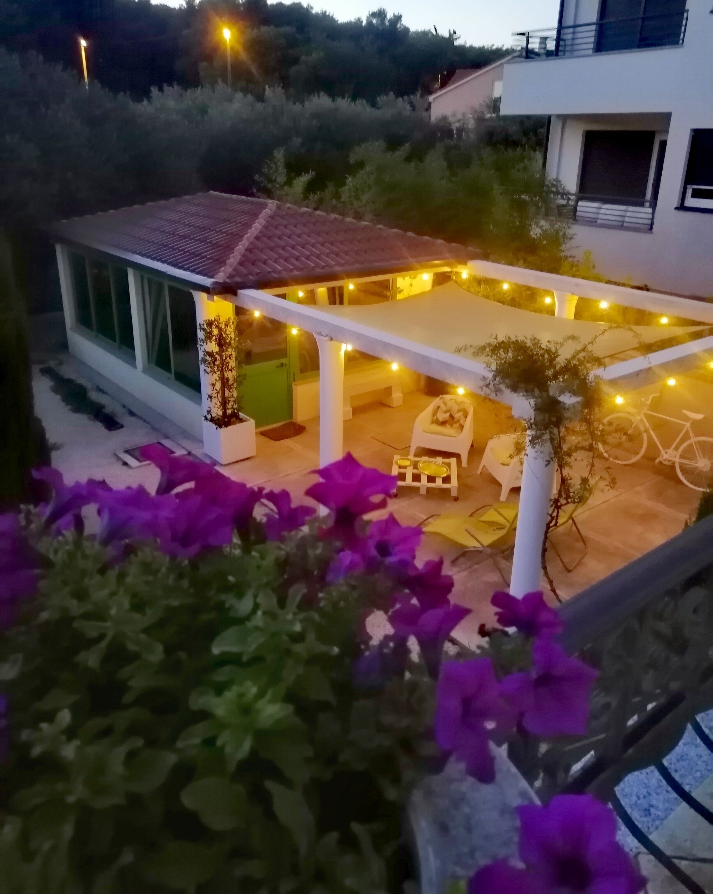 A modern outdoor patio area with string lights, a covered seating area, and a bicycle.