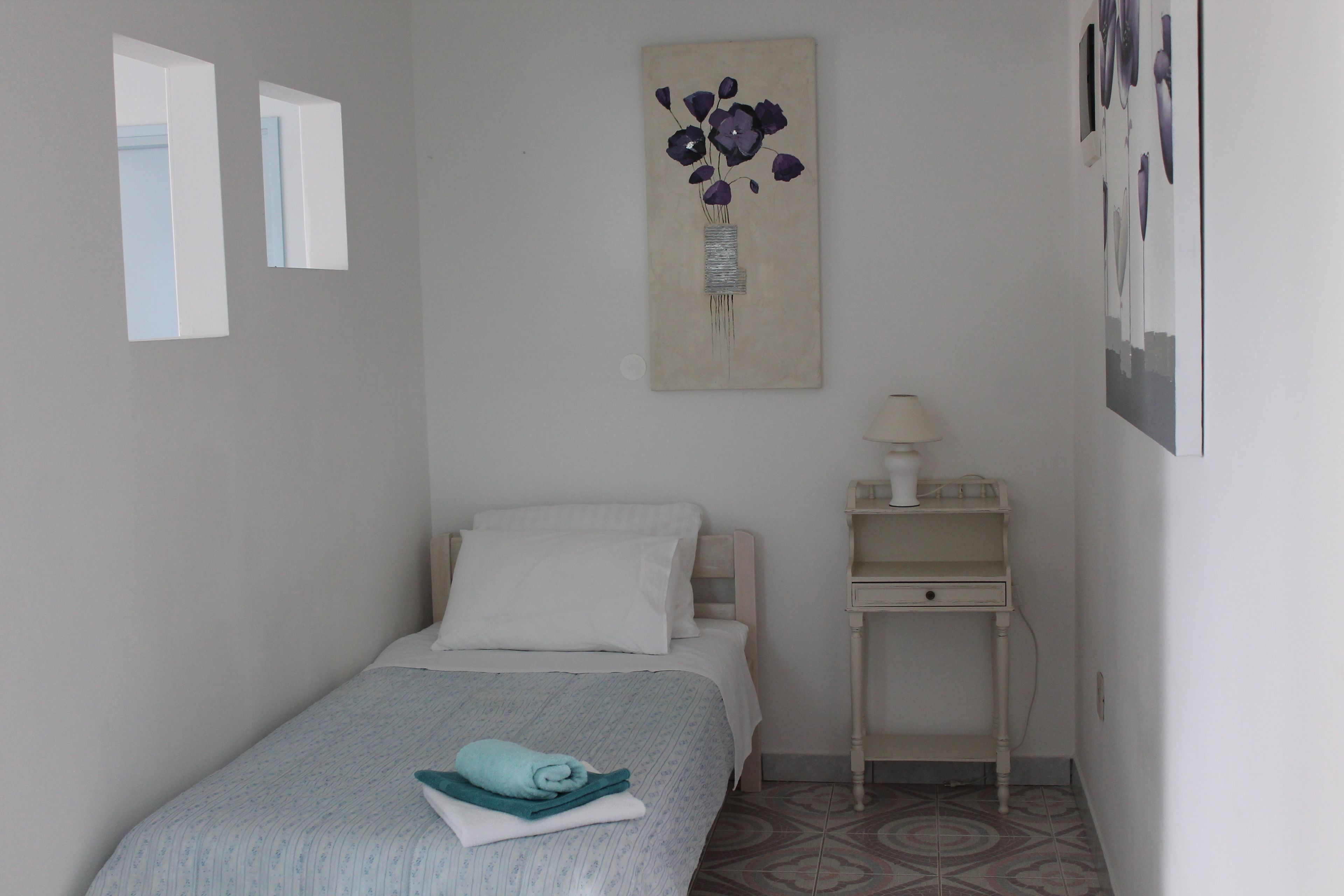 Une chambre à coucher comprenant un lit, une table de chevet, une œuvre d’art accrochée au mur et une porte.