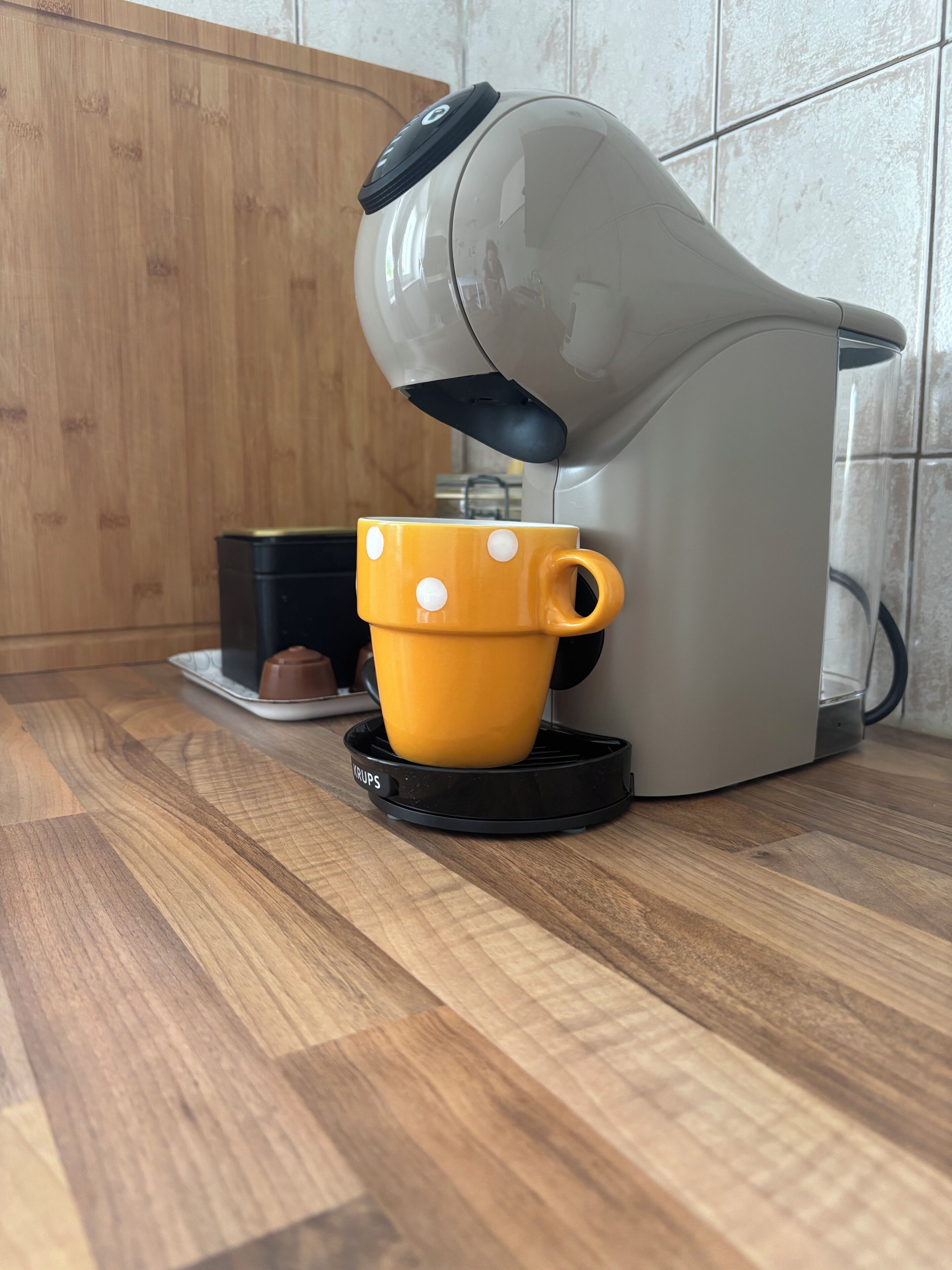 En kaffemaskine på en køkkenbordplade med en gul kop i drypbakken.